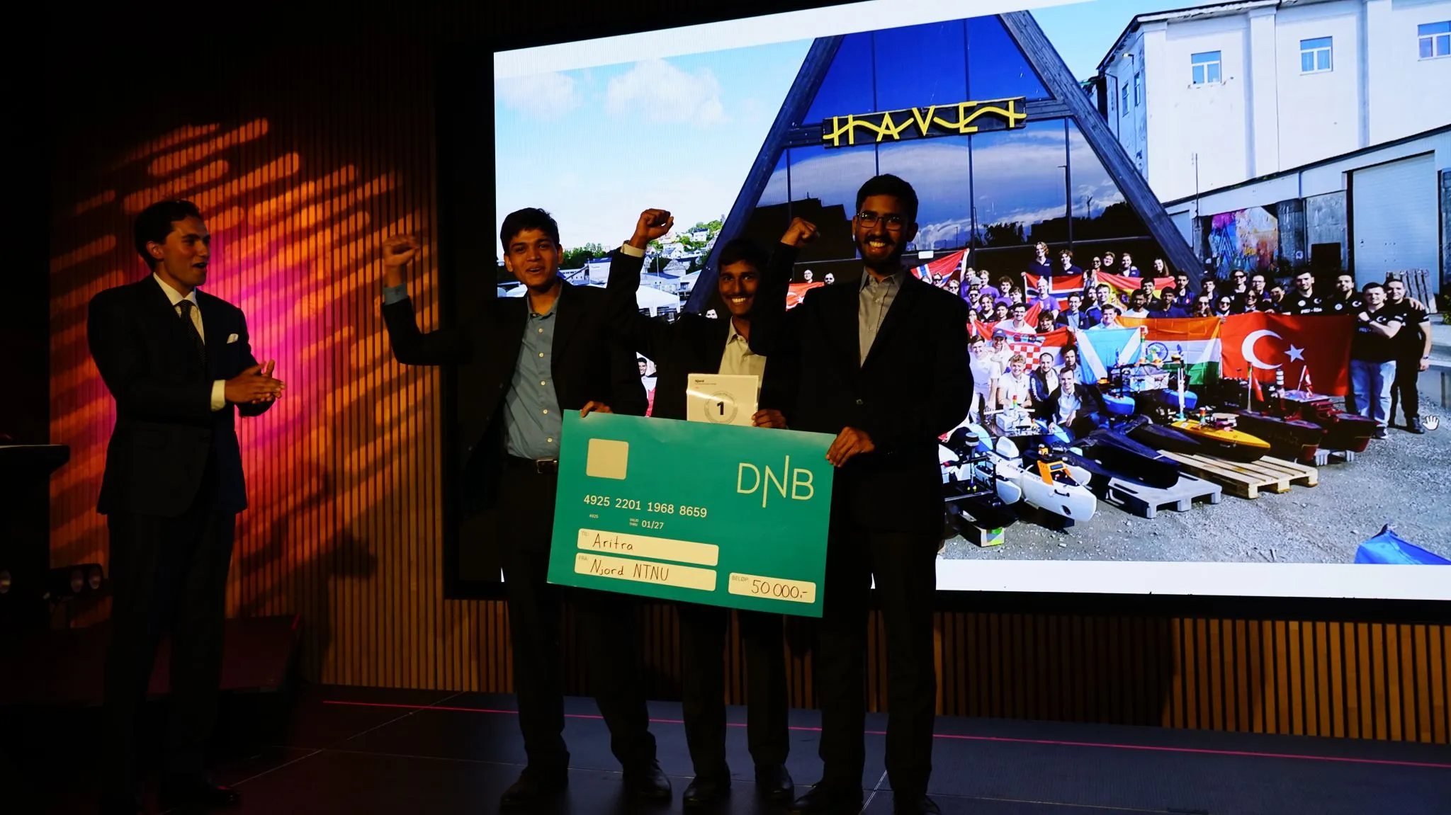 Team Aritra on stage holding the first-place card and ceremonial prize cheque